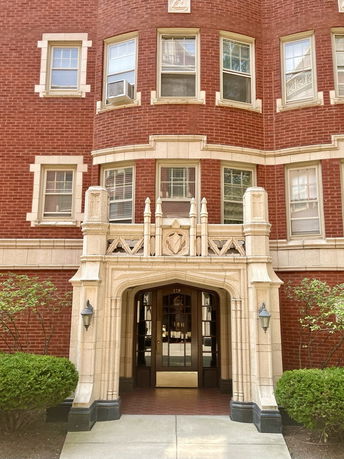 Front view of a brick apartment building with an ornate entrance.