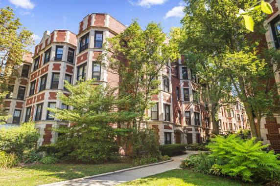 Front view of a multi-story brick apartment building with bay windows.