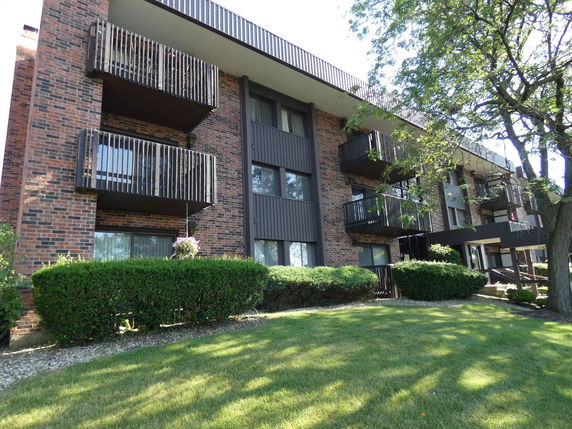 Front view of an apartment building with balconies and brick exterior.