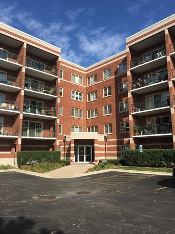 Front view of a multi-story brick apartment building with balconies.