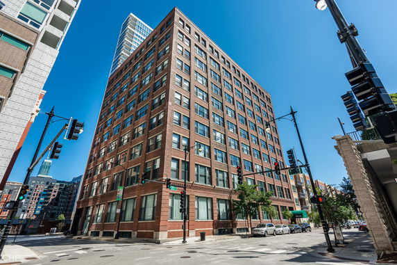 Front view of a multi-story brick building at a street intersection.