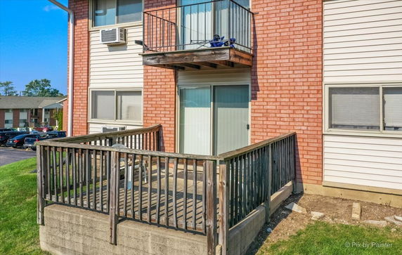 Front view of a building with a small balcony and ground-level patio.