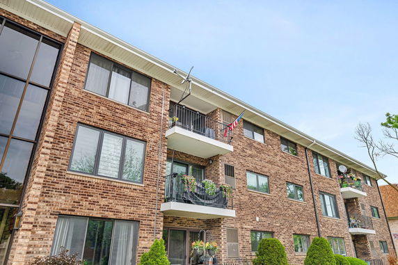 Front view of a three-story brick apartment building with balconies.