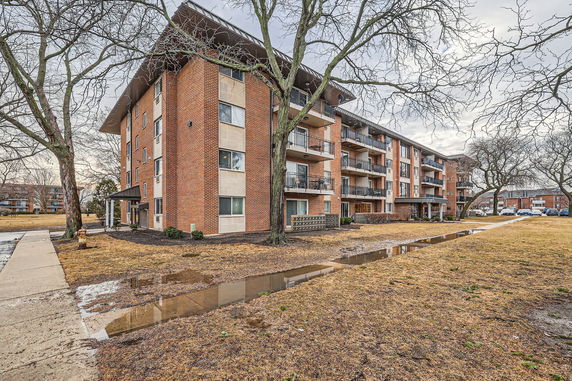 Front view of a multi-story brick apartment building with balconies.