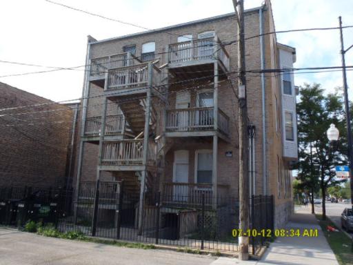 Rear view of a multi-story brick apartment building with balconies and external staircases.