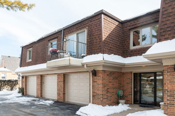 Front view of a two-story brick building with a balcony and garage doors.