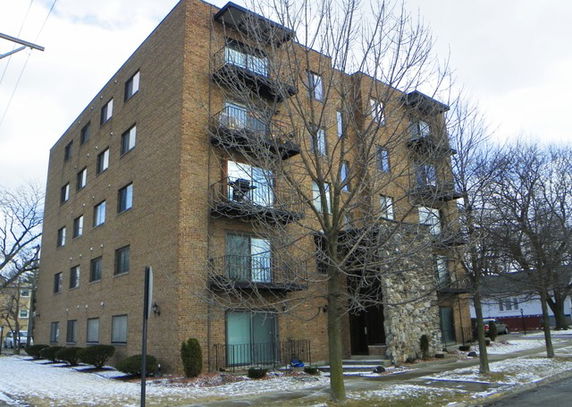 Front view of a multi-story brick apartment building with balconies.