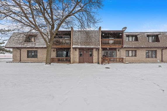Front view of a two-story building with a brown exterior and a central entrance, surrounded by snow.