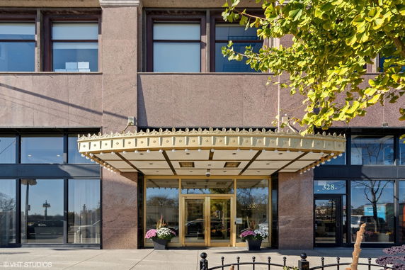 Front view of a building entrance with a decorative canopy and glass doors.