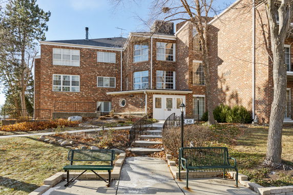 Front view of a multi-story brick building with large windows and an entrance path.