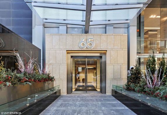 Entrance view of a building with glass doors and a prominent number 65 above it.