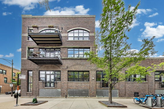 Front view of a brick building with balconies and large windows.