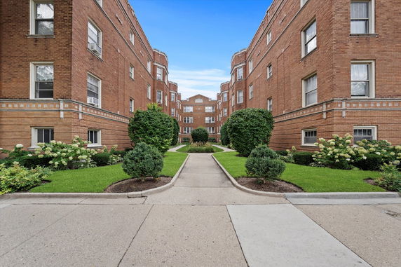 Front view of brick apartment buildings with green landscaping.