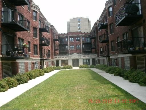 Front view of a multi-story apartment building with brick facade and balconies.