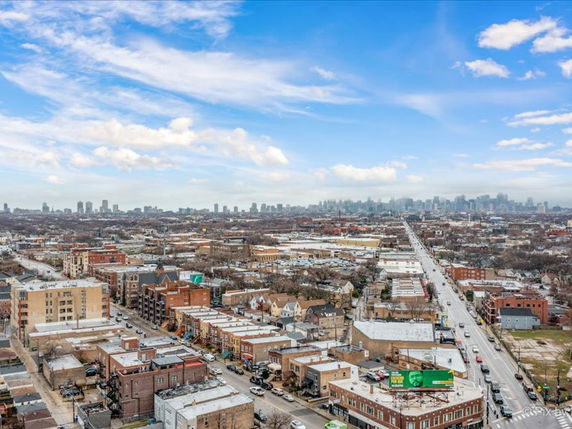 Wide-angle view of a cityscape with roads and buildings stretching into the distance under a blue sky.