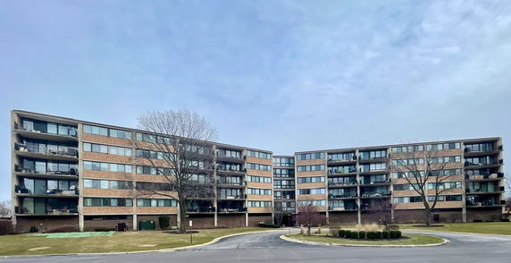 Front view of two connected mid-rise apartment buildings with multiple floors and balconies.