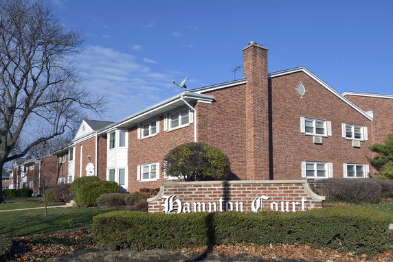 Front view of a brick residential building with multiple windows and a chimney.