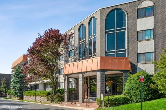 Front view of a multi-story building with large arched windows and a copper-colored awning.
