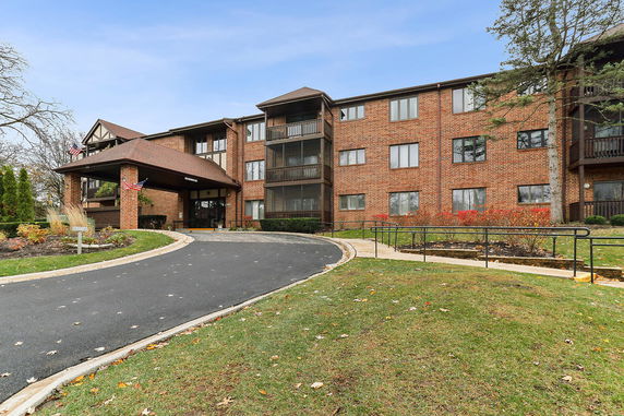 Front view of a multi-story brick apartment building with balconies and an arched entrance.