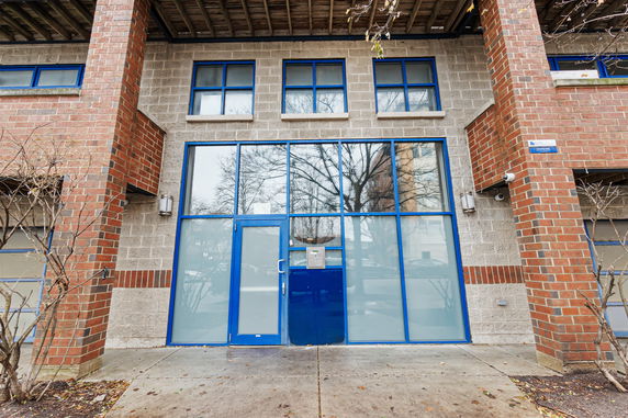 Front view of a modern two-story building with brick and concrete design, featuring blue-framed windows.
