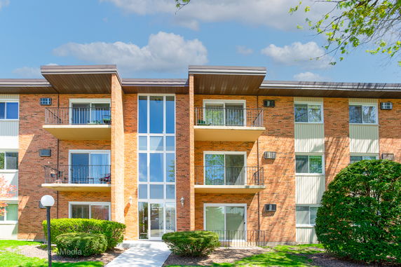 Front view of a multi-story brick apartment building with balconies.