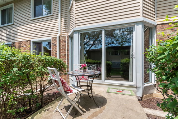 Front view of a house with large sliding glass doors and a small outdoor seating area.