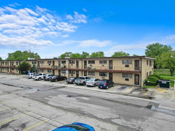 Front view of a two-story apartment building with a parking area in front.