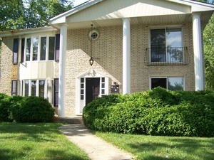 Front view of a two-story house with brick facade and white columns.