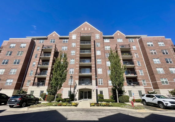 Front view of a multi-story brick apartment building with balconies.