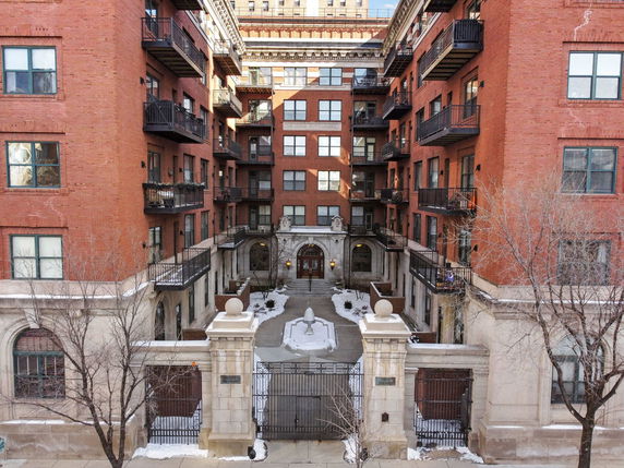 Front view of a multi-story brick apartment building with balconies.