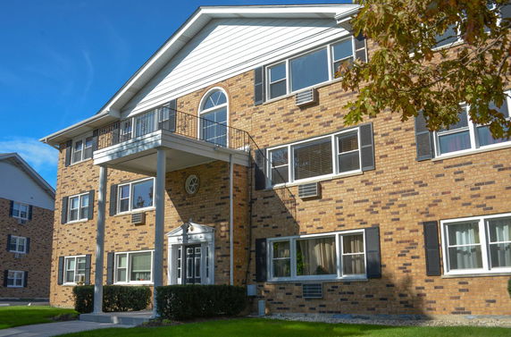Front view of a multi-story brick apartment building with a prominent entrance.