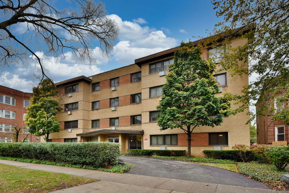 Front view of a four-story apartment building with a mix of brick and panel exterior.
