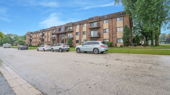 Front view of a multi-story brick apartment building with balconies.
