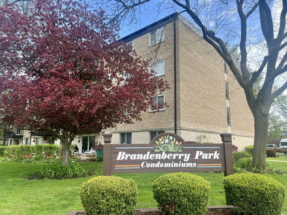 Front view of a multi-story condominium building with a sign for Brandenberry Park.