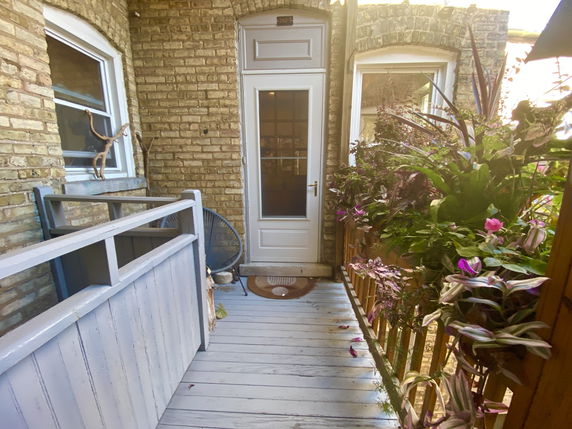 Small balcony with wooden decking and potted plants.