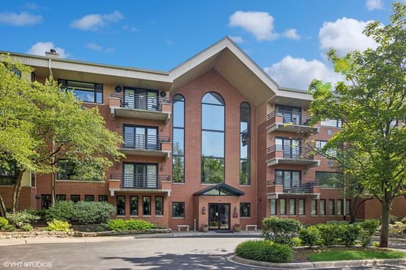 Front view of a multi-story building with red brick exterior and balconies.