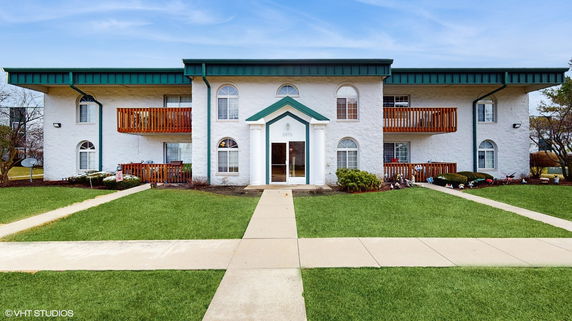 Front view of a two-story apartment building with a central entrance and balconies.