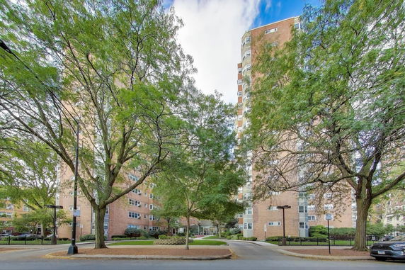 Front view of a multi-story apartment building with trees in the foreground.