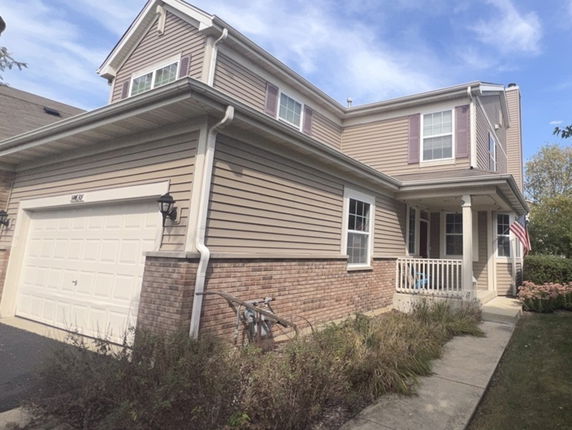 Front view of a two-story house with a garage and a small porch.