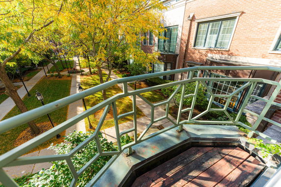 View from a balcony overlooking a garden area with pathways and trees.