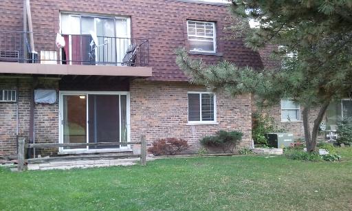 Front view of a two-story brick building with a balcony and sliding glass door.