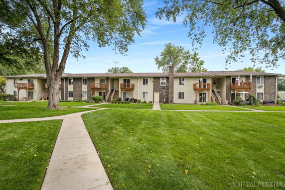 Front view of a two-story apartment complex with balconies and a central walkway.