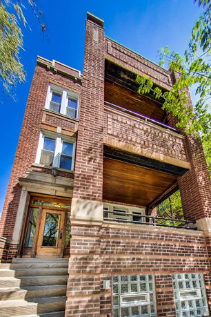 Front view of a multi-story brick building with wooden entrance door and balconies.