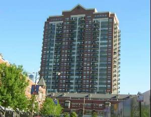 Front view of a tall residential building with multiple balconies.