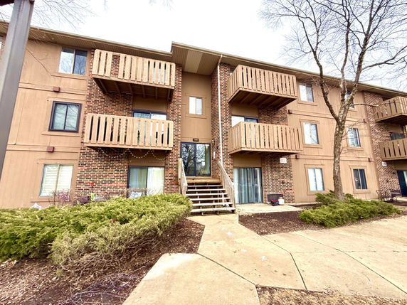 Front view of a three-story apartment building with balconies and brick facade.