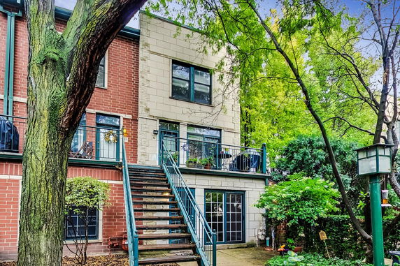 Front view of a multi-story house with stairs leading to an upper balcony.
