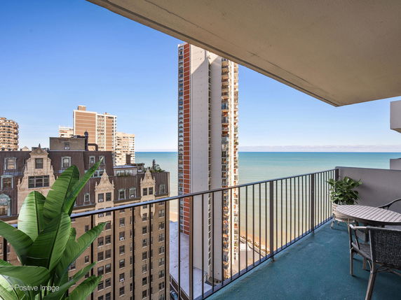 Balcony view overlooking the ocean and nearby high-rise buildings.