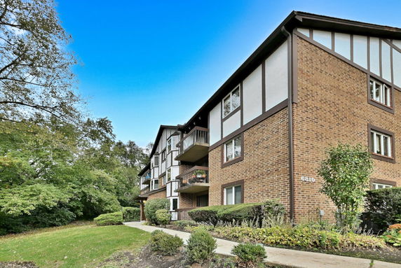 Front view of a multi-story brick apartment building with balconies.