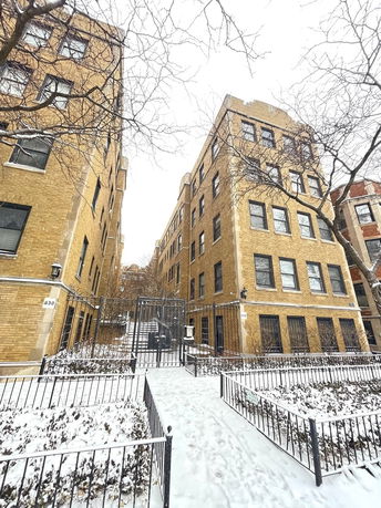 Front view of a multi-story building with a brick facade and a gated entrance.