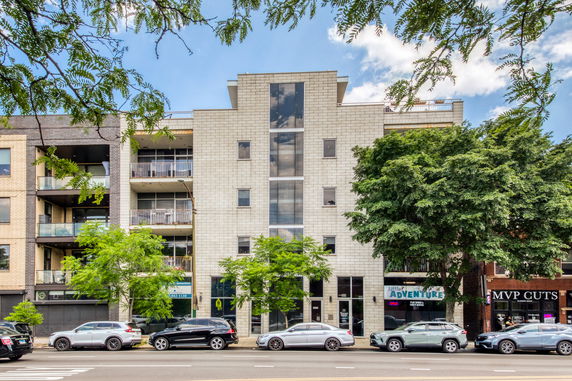 Front view of a multi-story building with balconies and large windows.
